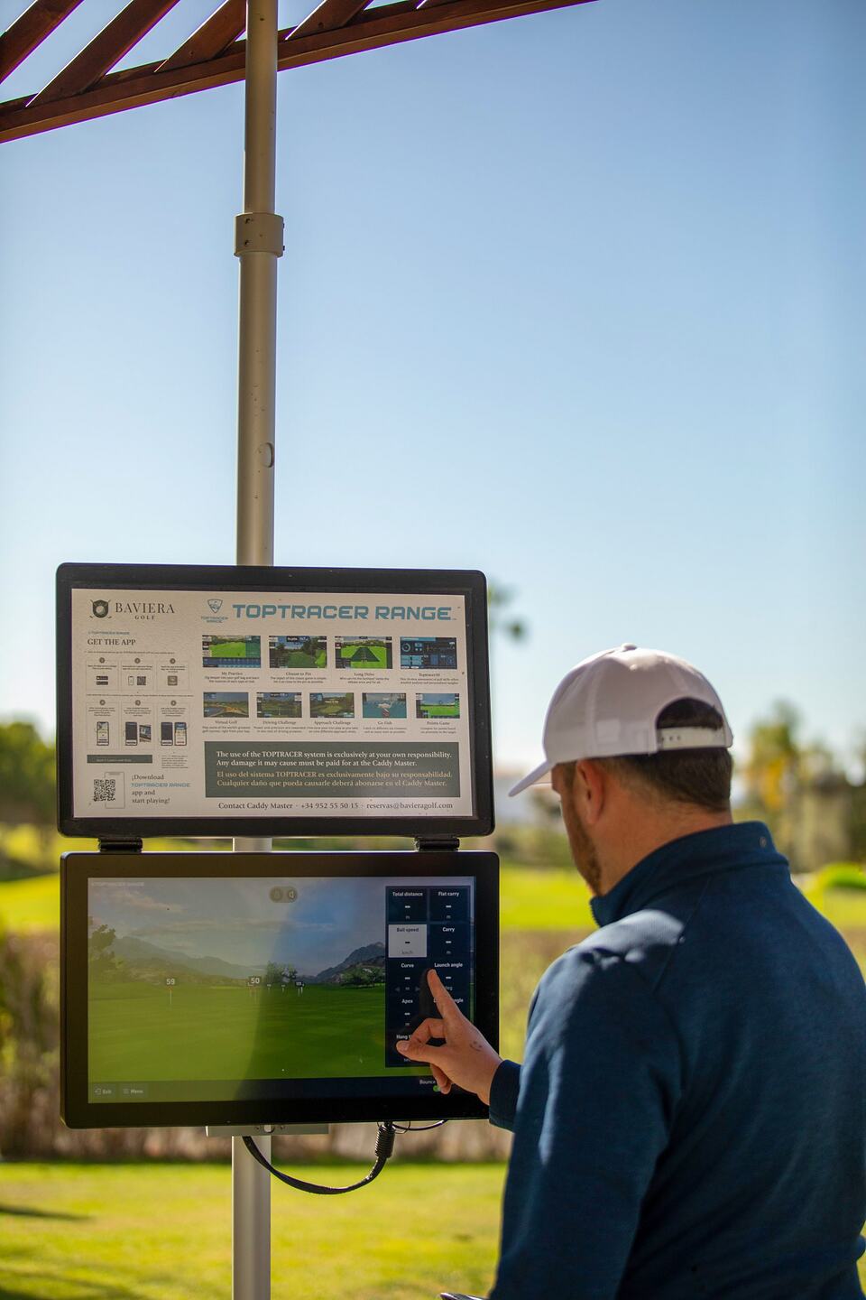 Golfer using a Toptracer Range touchscreen at Baviera Golf