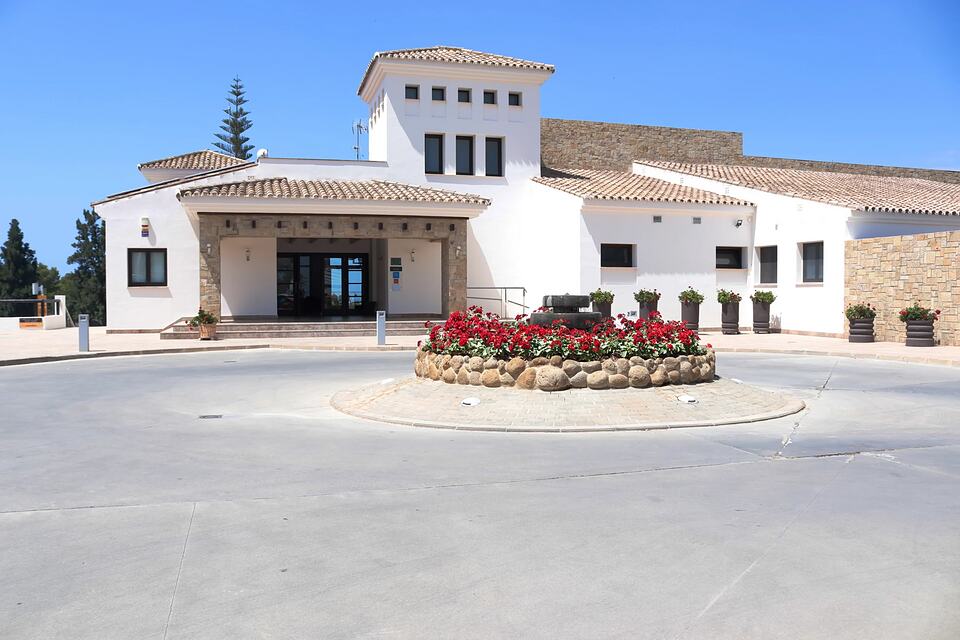 Baviera Golf clubhouse entrance with white walls, stone accents and a flower planter