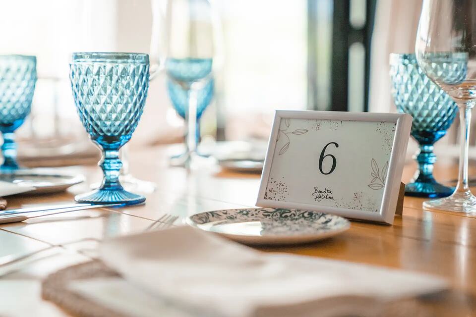 Wedding reception table set with blue glasses, patterned plates and a table number card
