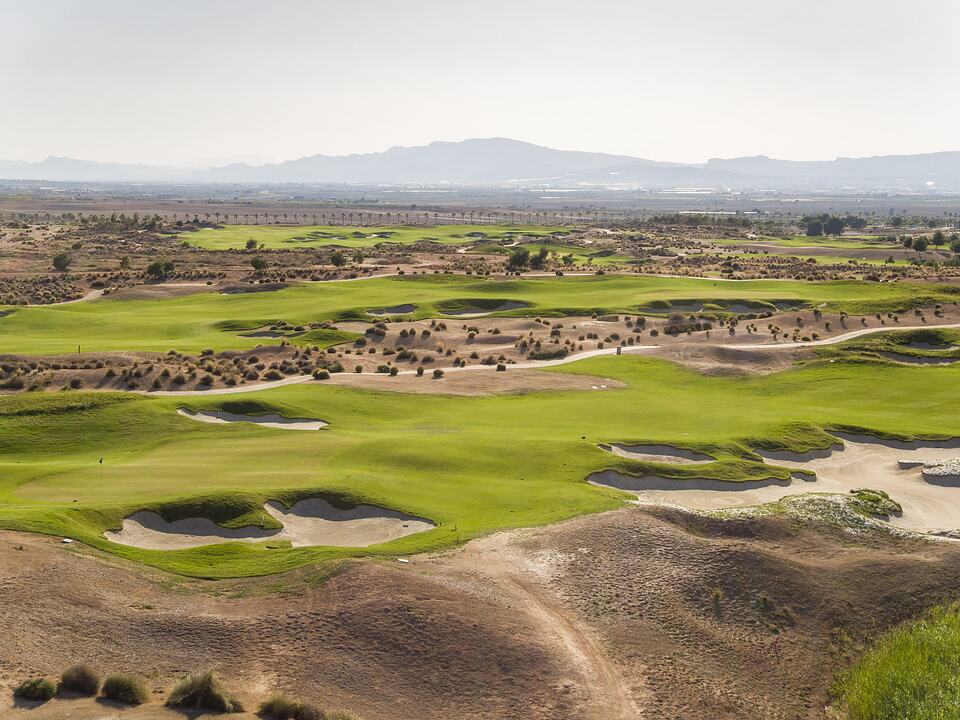 Fairways and sand bunkers across the Alhama Signature Golf course, with hills in the distance