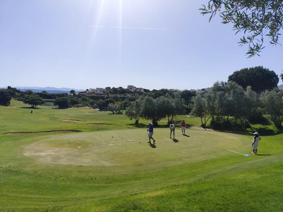 Golfers playing on a green at Antequera Golf, with rolling fairways and trees in the background.