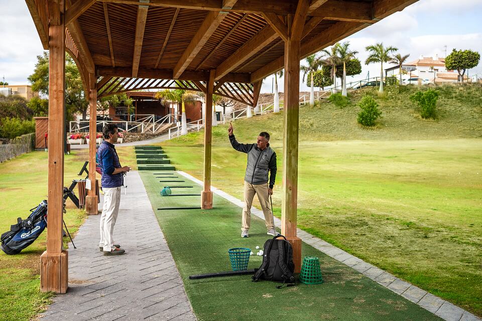 A golf instructor talks with a student at the covered practice range.
