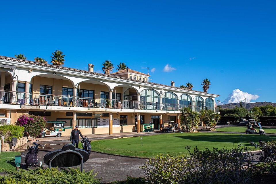 Golf Bonalba clubhouse beside the putting green, with golf carts and bags outside