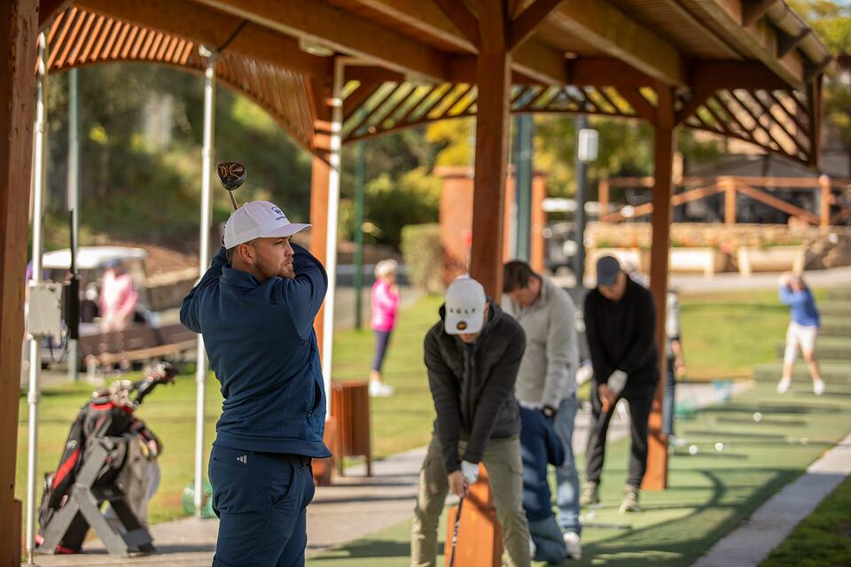 Golfers practicing their swings at the covered driving range