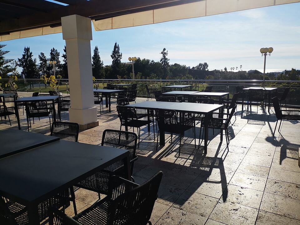 Outdoor restaurant terrace with tables and chairs overlooking greenery at Baviera Golf