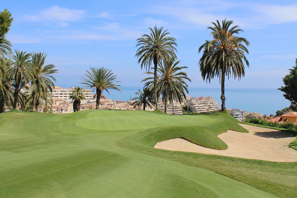 A palm-lined green and bunker overlooking the Mediterranean at Golf Torrequebrada.