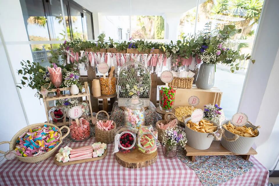 A party buffet decorated with flowers, sweets and bowls of snacks