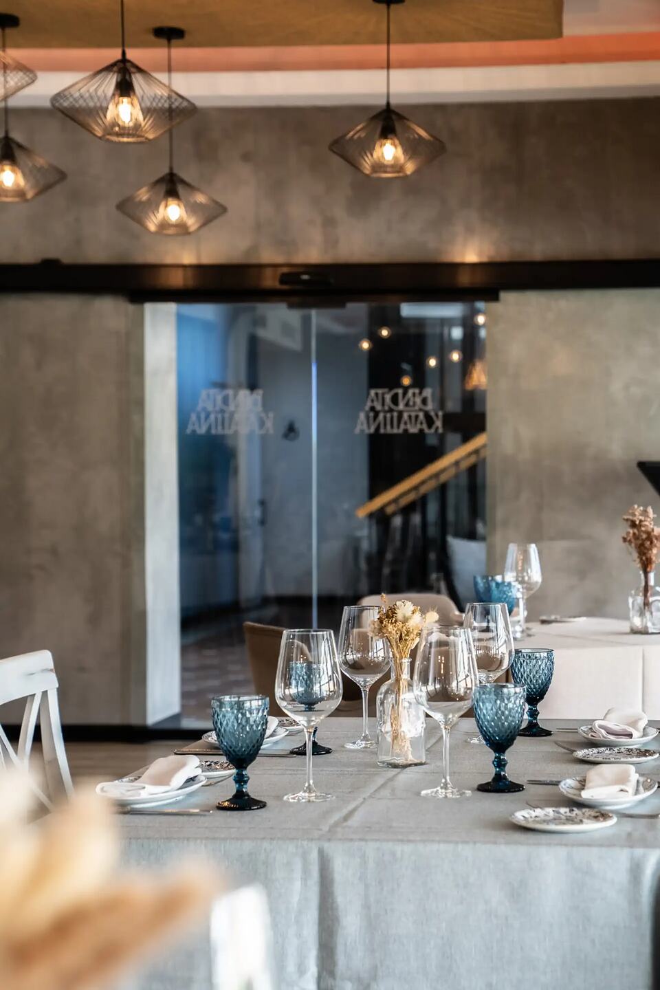 Restaurant dining room with a set table, wine glasses and pendant lights