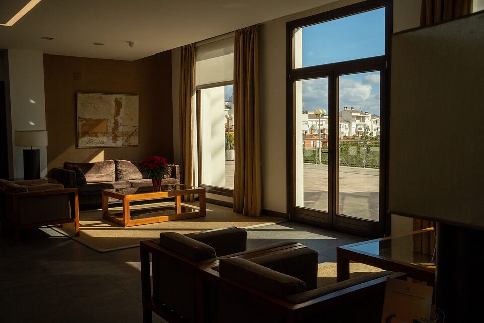 Sunlit lounge with sofas and a coffee table beside doors opening onto a terrace.