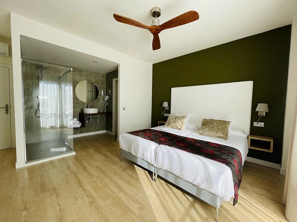 Hotel room with a double bed and an open bathroom with a glass shower