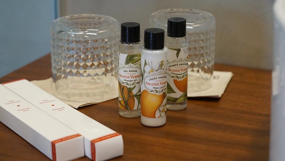 Toiletries and drinking glasses arranged on a wooden hotel-room table.