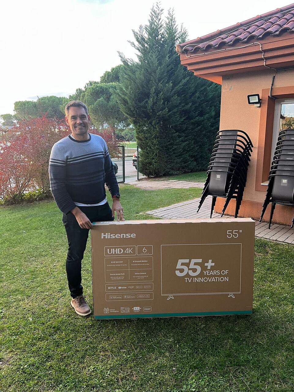 A man stands beside a large television box on the lawn outside the clubhouse.