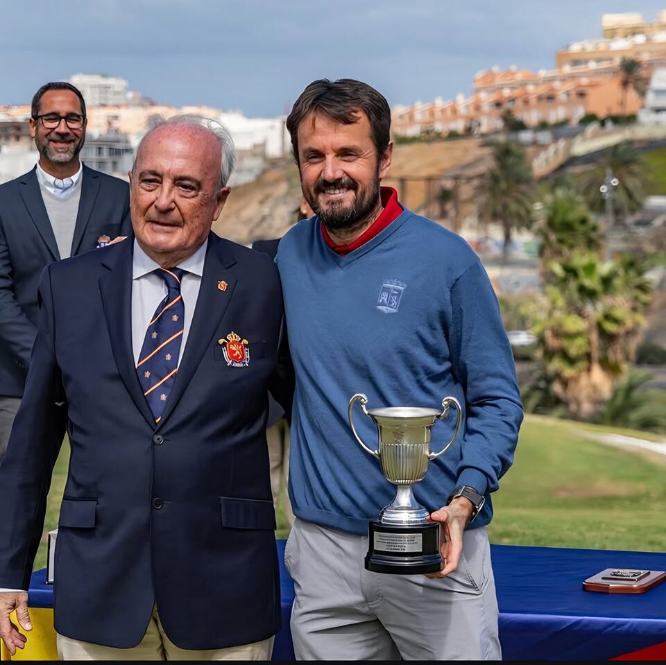 Pitch-and-putt champion Jose Mª Ortiz de Pinedo holds a trophy beside an event official.