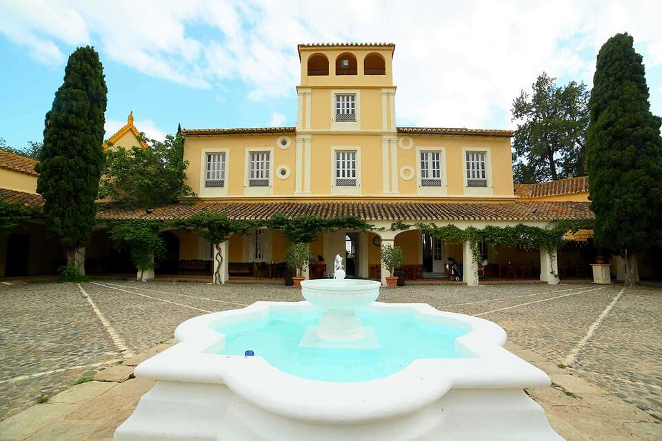 Yellow clubhouse facade behind a white fountain in the courtyard