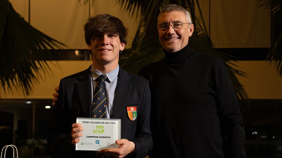 Un joven ganador sostiene su premio junto a un hombre mayor en el torneo solidario de golf de 2025.