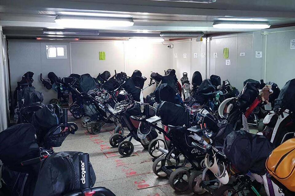 Golf bags and trolleys stored in a covered equipment room at Aldeamayor Club de Golf