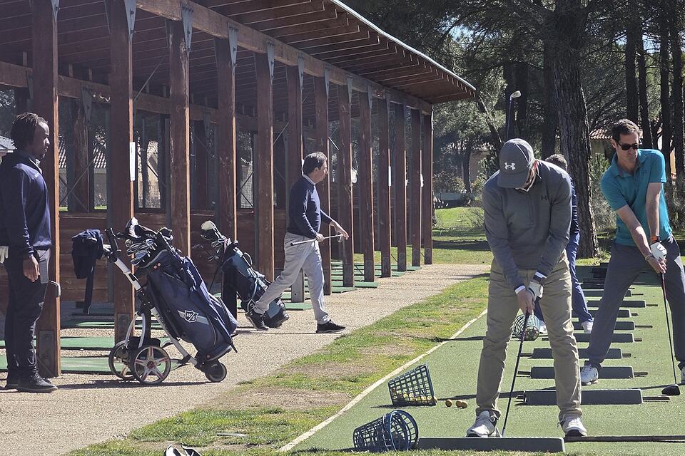 Golfers practise their swings on the driving range beside the covered bays.