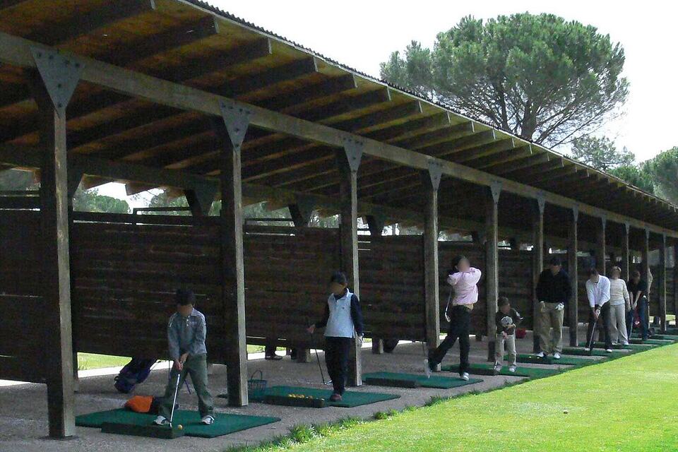 Golfers practising at covered driving range bays at Aldeamayor Club de Golf