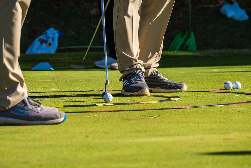 Golfers practicing putting on a green, with golf balls and training markers