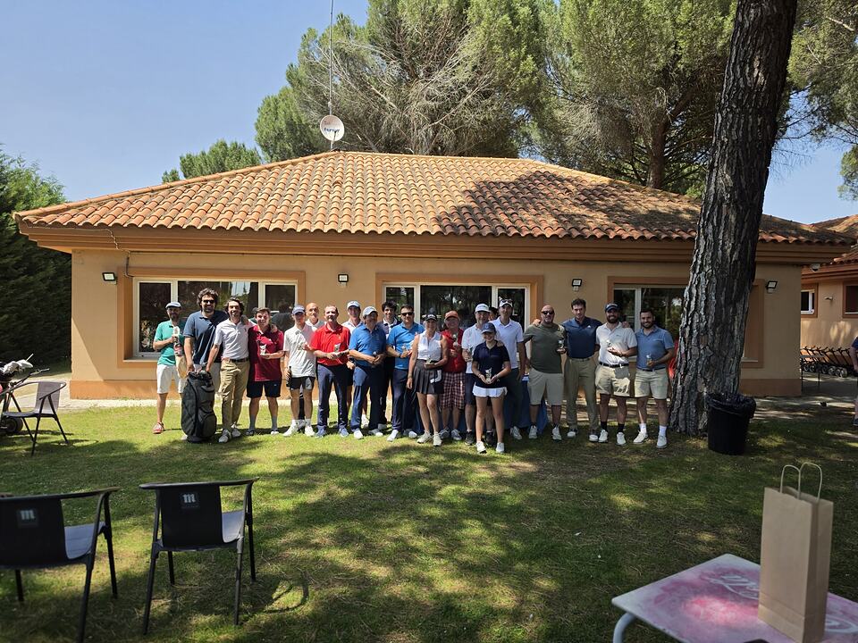 A group of golfers poses in front of a clubhouse at Aldeamayor Club de Golf.