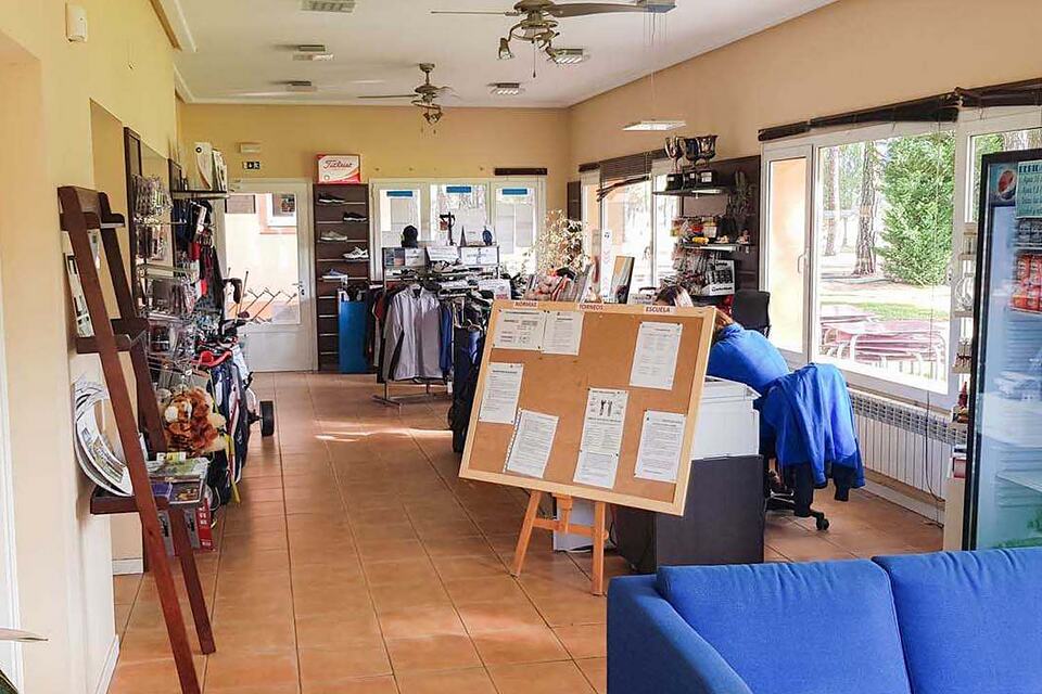 Interior of the golf club shop with golf equipment, clothing and accessories on display.